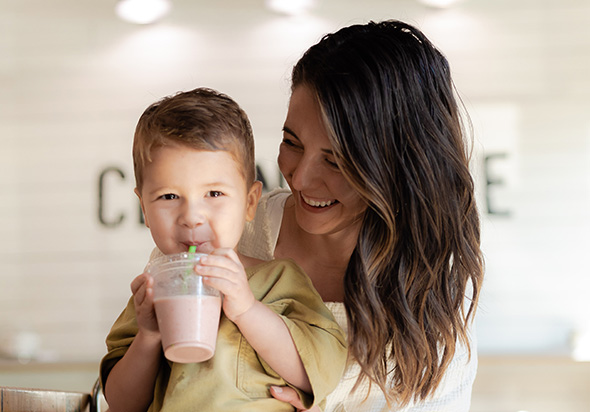 Clean Juice Mom with Kid on lap holding a smoothies